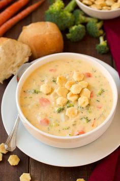 a white bowl filled with soup next to some vegetables and bread on a table top