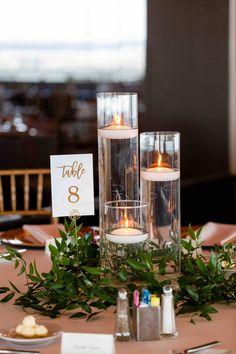 the centerpieces are filled with candles and greenery