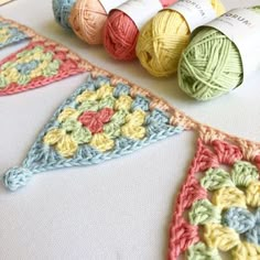 several balls of yarn sitting on top of a table next to crocheted pennants