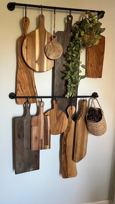 wooden cutting boards hanging on a wall with potted plants and other kitchen utensils