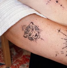 two people with tattoos on their arms, one has a tiger and the other has fireworks