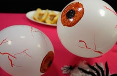 two white balloons with red paint on them and some other decorations in front of them