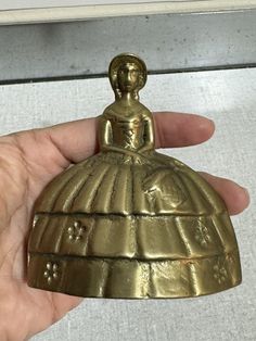 a hand holding a gold bell shaped object