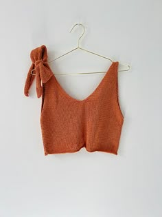 an orange crop top hanging on a clothes hanger with a knot at the back