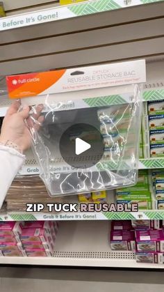 a person is holding up a plastic bag in a store display case that says zip tuck reusable