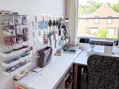 a sewing studio with lots of crafting supplies on the desk and in front of a window