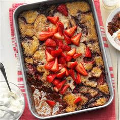 a dessert with strawberries on top is sitting next to other foods and utensils