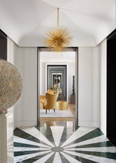 an elegant hallway with black and white marble flooring, gold chandelier and yellow chairs