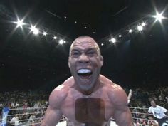 a wrestler with his mouth open in the middle of a wrestling ring, surrounded by fans