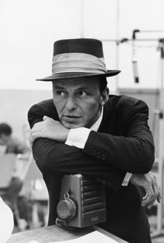 black and white photograph of a man with his arms crossed, leaning on a radio