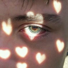 a young man's eyes are shown through the shadows of hearts on his face