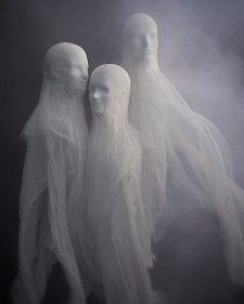 three white mannequins with long hair standing in fog