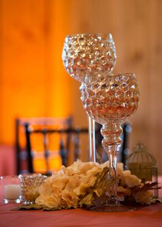 two crystal goblets sitting on top of a table next to flowers and candles