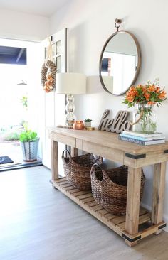 a wooden table with baskets on it and a mirror hanging above the table in front of it