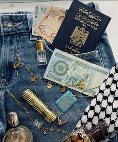 the contents of a purse are laid out on top of a pair of blue jeans