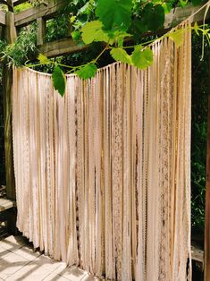 an outdoor area with a wooden fence and lots of curtains hanging from the side of it