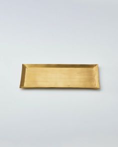 a rectangular brass plate on a white background, with the edge slightly bent to reveal an empty space