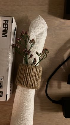 a white napkin wrapped in twine and tied with rope is sitting on a table next to a box