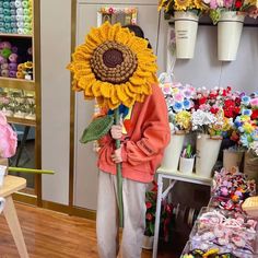 a person standing in front of a store holding a large sunflower