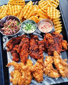 fried chicken, french fries and coleslaw are served on a tray with dipping sauces