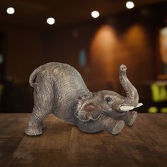 an elephant figurine laying on top of a wooden table next to a wall