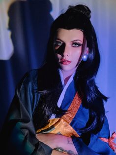 a woman with long black hair wearing a blue and orange kimono