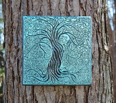 a metal plaque with a woman's face on it in front of a tree