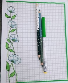 two pencils sitting on top of a piece of paper with flowers drawn on it