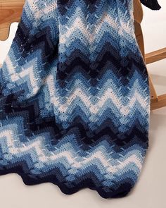 a blue and white knitted blanket sitting on top of a wooden chair next to a rocking chair