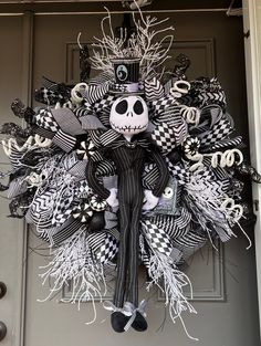 a wreath with a skeleton on it and black and white decorations hanging from the front door