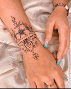 a woman's hand with a flower tattoo on her left arm and the wrist