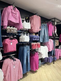 a clothing store with lots of different colored shirts and jeans on display in front of the rack