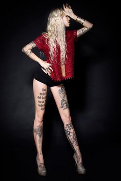 a woman with long hair and tattoos on her body is posing for the camera,