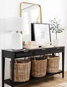 a black console table with wicker baskets under a mirror