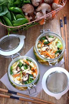 two glass jars filled with food sitting on top of a wooden table next to chopsticks