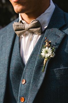 a man in a suit and bow tie with a boutonniere on his lapel