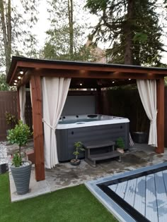 an outdoor hot tub in the middle of a backyard with curtains on it's sides