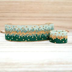 two green and gold beaded bracelets sitting on top of a wooden table next to each other