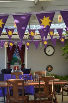 purple and yellow bunting hanging from the ceiling in a dining room with wooden table and chairs