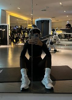 a woman taking a selfie while sitting on the floor in front of a mirror