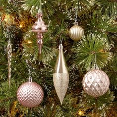 christmas ornaments hanging from the branches of a pine tree in gold, silver and white