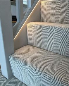 the stairs are lined with herringbone carpet and illuminated by led lights in this modern home