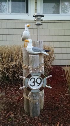 two seagulls sitting on top of a wooden pole next to a sign with the number thirty