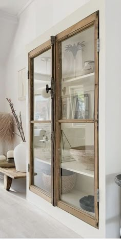 an empty room with two glass doors and some shelves on the wall in front of it