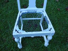 an old chair sitting in the grass on top of it's legs and feet