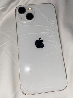 an iphone that has been broken and is laying on a white sheet with the screen cracked off