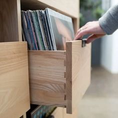 a person holding a record player in a wooden drawer filled with vinyls and cds