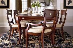 a dinning room table with chairs and a rug on the floor in front of it