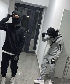 two men in black and white outfits standing next to each other on the hallway way