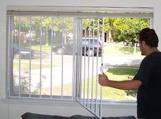 a man standing in front of a window holding onto the bars that are attached to it